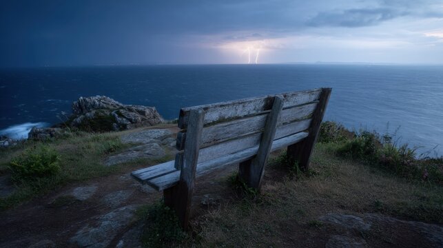 A wooden bench on the top of a cliff, overlooking the sea, rocks, and plants. The dark sky is filled with lightning overhead. Hyper-realistic photography.  - Powered by Adobe