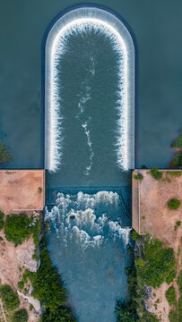 Aerial view of the water gushing over a dam's edge, creating a frothy spectacle against the serene waters, along Zuma Barracks, Suleja, Niger, Nigeria.