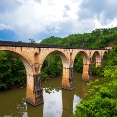 Fototapeta premium Ancient stone-arch bridge over a calm river, lush