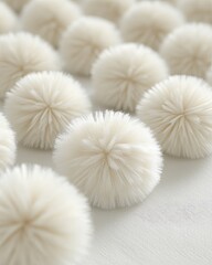Fuzzy, cream-colored pom-poms aligned on a light surface