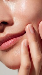 Close-up of a woman examining her skin with a soft smile while enjoying a skincare routine
