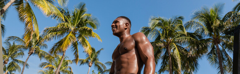 Muscular man exercising outdoors under palm trees in Miami 