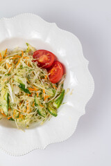 Top view of fresh salad with cabbage, carrots, and tomatoes.