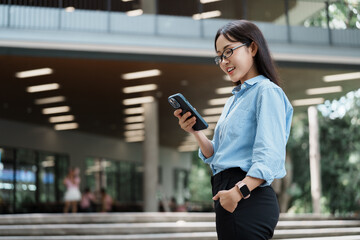 Obraz premium Young woman using smartphone in urban setting