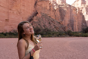 Young woman smiling with a glass of white wine in a red canyon