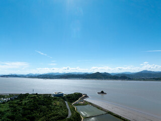 Aerial view of a coastal area with lush greenery, water, and distant islands