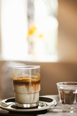  iced latte served by pouring hot espresso over iced milk, creating a beautiful layer instead of blending like a latte. vertical photo