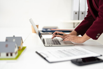 close-up hand of a woman working on her laptop computer, typing on the laptop keyboard, responding...