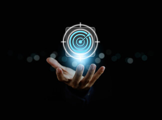 Hand holding glowing digital target with arrow, business goal, marketing strategy, and success concept symbolizing focus, achievement, and innovation in modern technology.
