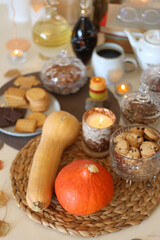 Lit candles, cookies, chocolate, nuts, tea, wine, pumpkins, books, reading glasses and autumn leaves on the table. Autumnal hygge at home. Selective focus.