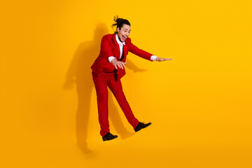 Funny man in red suit leaps across bright yellow studio background creating bold stylish fashion moment for promotion and advertising