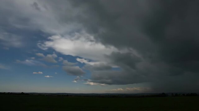 Dark storm clouds forming over green fields in the concept of Nature  