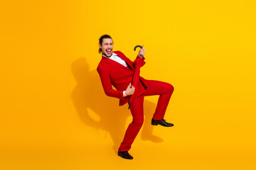 Funny stylish man jumps in bold red suit with umbrella against bright yellow background for dynamic stock image