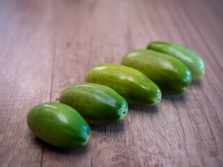 Fresh green plum tomatoes on a wooden table. Unripe tomatoes suitable for pickling, chutney, or to let ripen naturally.