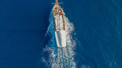 Sailing Vessel on the Blue Sea: A traditional wooden sailing vessel gracefully glides across the tranquil expanse of the azure sea. © ALPSARAL