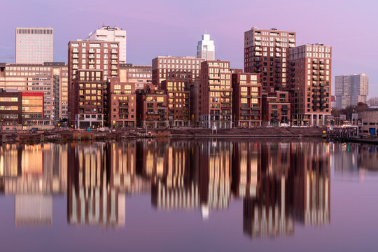 City skyline reflects in water at sunset