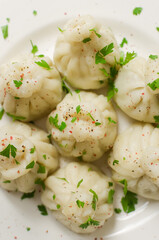 Boiled khinkali on a ceramic plate. Minimalism style. Traditional Georgian cuisine concept. Vertical orientation. Selective focus. Copy space
