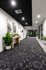 Modern hallway with art, plants, and recessed lighting, leading to a glass-walled area