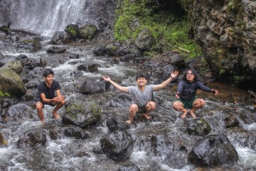 Joyful Friends Embrace Nature's Refreshing Embrace By Waterfall