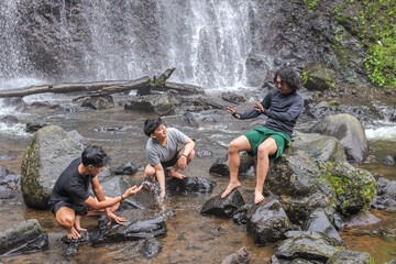 Adventurous Friends Enjoying Nature At Stunning Waterfall During Vibrant Summer Vacation