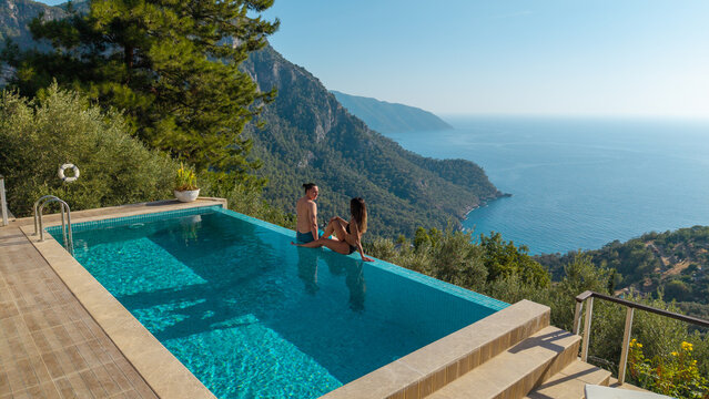 Elegant vacation lifestyle featuring a couple in an infinity pool with sea view