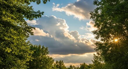 Obraz premium Sunlight breaks through dramatic clouds framed by lush green trees in a serene natural landscape