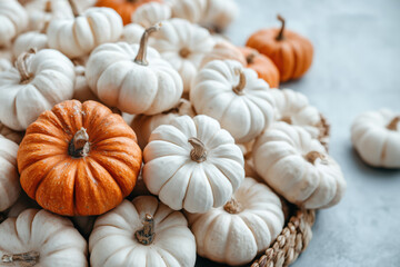 A pile of white pumpkins and a few orange ones on a wicker basket