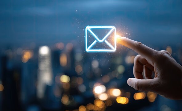 A finger touching an illuminated email icon against a blurred cityscape at night