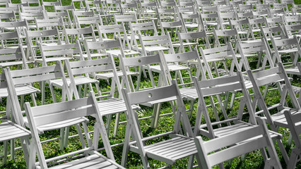 Rows of white folding chairs on green grass outdoors