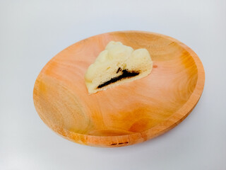 Half of Bakpao or Chinese Steamed Bun served on a wooden plate. Isolated on white background.