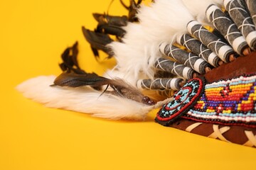 Traditional warbonnet (Native American chief headdress) on yellow background, closeup