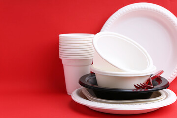 Set of disposable plastic tableware on red background, closeup. Space for text