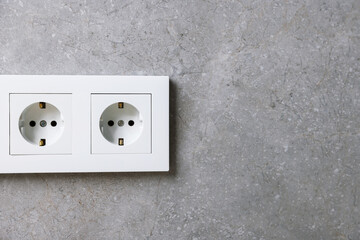 Electric power sockets on grey wall, space for text