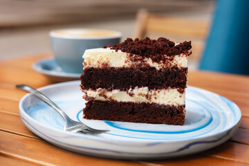 Slice of tasty cake and fork on wooden table, closeup
