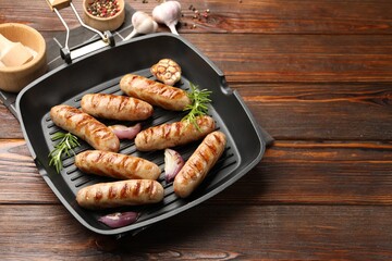 Pan with grilled sausages and spices on wooden table