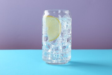 Refreshing water with lemon and ice on color background, closeup