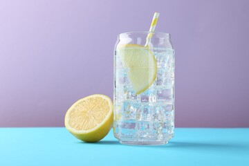 Refreshing lemon water with ice in glass and fresh citrus fruits on color background