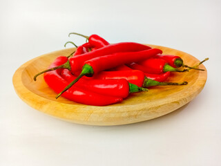 Red chili peppers served on a wooden plate, isolated on a white background.