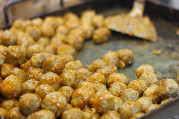 Spicy meatballs cooking in pan. Asian street food close up.