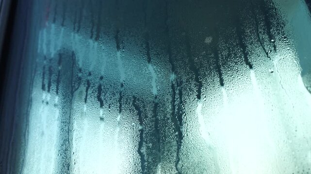 Water condensation forming streaks on glass surface, macro texture illustrating humidity, temperature difference, vapor accumulation and moisture process in physics, climate or ventilation context