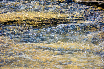 nature texture with stones in the water steam. closeup background of a river shore in autumn