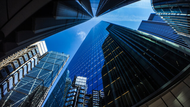 Modern skyscrapers and glass office buildings in business district, captured from low angle perspective with blue sky, symbolizing architecture, urban growth, corporate success, and city development.