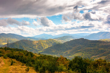 autumn landscape in mountains. beautiful view of countryside in europe. colorful carpathian alps of ukraine in the background. cloudy sky. picturesque rural scenery with village in the valley