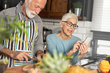 Senior couple in kitchen with smartphone