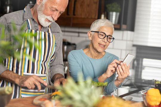 Senior couple in kitchen with smartphone