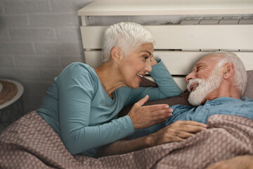 Affectionate happy mature couple in bed