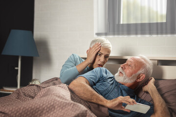 Senior couple with smartphone having quarrel and marriage conflict because of cheating