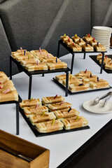 Buffet catering with assorted sandwiches on trays, party finger food and appetizers on a white table at corporate event