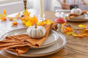 Autumn, fall, Halloween or thanksgiving day festive table setting. Fallen leaves, pumpkins and napkin on plate on wooden table background.