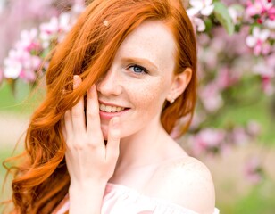 Fototapeta premium Woman with red hair in a spring blossom garden